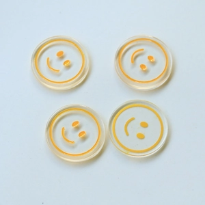 Detailed view of four transparent round resin smile face charms for DIY jewelry making