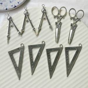 Macro shot of vintage silver alloy stationery charms including compasses and scissors