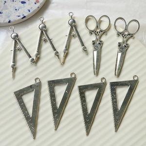 Detailed macro view of vintage zinc alloy charms showing ruler and compass textures