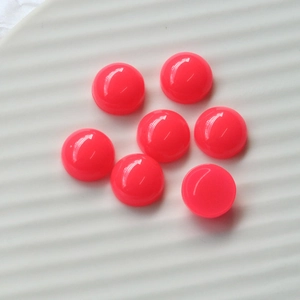 Macro shot of seven 12mm neon pink resin heart-shaped cabochons on a white ceramic plate