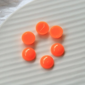 Close-up of six glossy 12mm fluorescent orange resin heart cabochons on white textured plate