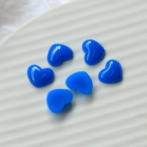 Macro view of six shiny 12mm blue resin heart charms in a white decorative ceramic dish