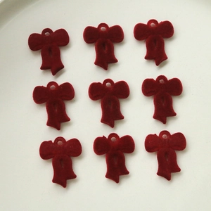 Dettaglio di nove ciondoli a fiocco rosso floccato con passanti per creazione gioielli fai-da-te