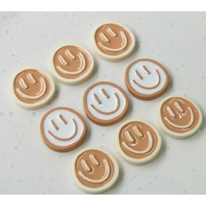Macro detail of round resin smiley charms in cream and coffee colors for DIY jewelry