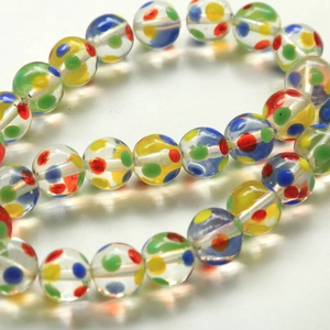 Macro shot of transparent glass beads with colorful rainbow polka dots on white cord
