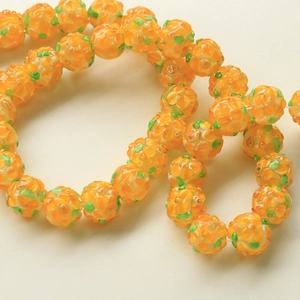 Macro shot of vibrant orange glass flower beads with yellow petals for DIY jewelry making