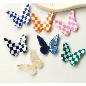 Flat lay of resin butterfly charms with checkerboard and gold foil patterns for DIY crafts