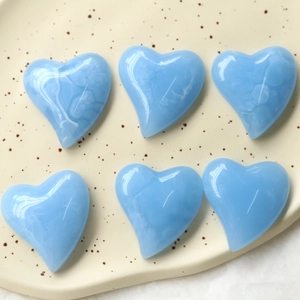 Dettaglio macro di ciondoli a cuore blu cielo con texture marmorea su vassoio
