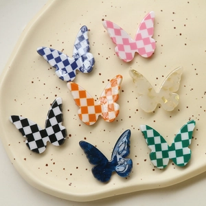 Detailed view of checkerboard and marble pattern resin butterfly accessories on a ceramic plate