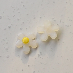 Detailed macro view of two translucent resin 5-petal flower charms for DIY jewelry and crafts