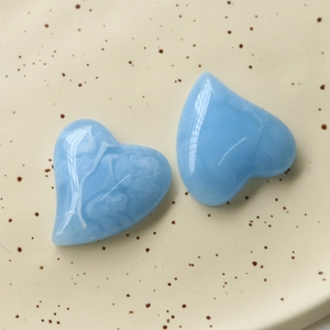 Vista macro di ciondoli a cuore in resina blu cielo marmorizzati su piatto ceramico