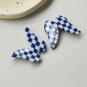 Macro view of blue and white checkerboard butterfly resin charms for DIY hair accessories