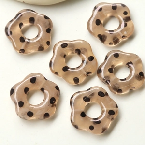 Vue détaillée de perles de fleurs en résine ambre translucide avec pois noirs pour bijoux DIY