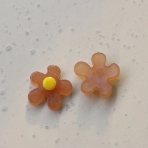 Detail of orange resin flower charms with yellow stamen for DIY jewelry making
