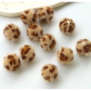 Macro detail of plush leopard print balls with golden tinsel for DIY jewelry making