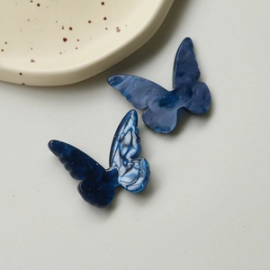 Close-up of resin butterfly accessories with blue marble texture for DIY jewelry making