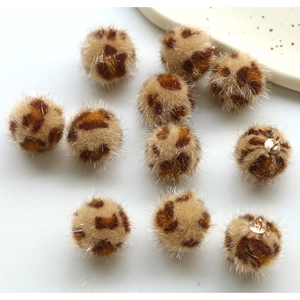 Detailed view of leopard print plush pom poms with metal loops for DIY jewelry making