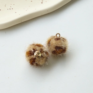 Close-up of leopard print faux fur plush balls with gold metal loops for DIY crafts