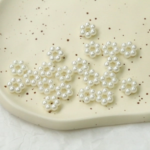 Macro shot of pearl white acrylic flower charms for jewelry DIY on ceramic tray