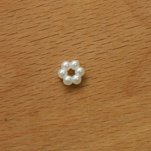 Detailed close-up of a DIY acrylic flower bead with pearls on a wooden background