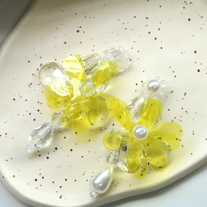 Handmade yellow resin flower earrings with pearls and crystal beads on a ceramic plate
