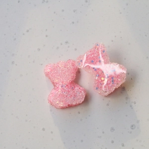 Dettaglio macro di ciondoli orsetto rosa in resina con paillettes iridescenti per DIY