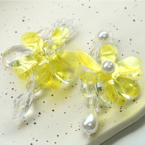 Close-up of yellow resin flower earrings with crystals and pearls for summer jewelry DIY