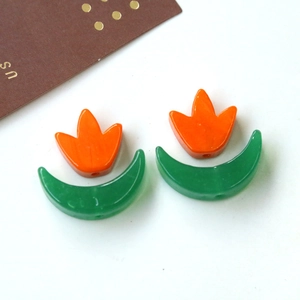 Dettaglio macro di perle in resina a tulipano arancio e luna verde per accessori gioielli DIY