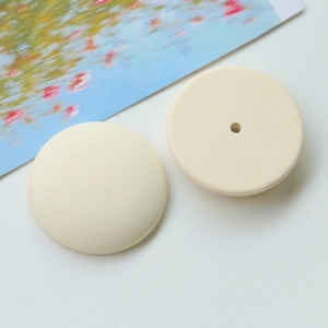 Detail of matte cream resin circular DIY beads with smooth edges for jewelry making