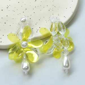 Detail of yellow flower earrings with clear beads and white drop pearls in a ceramic tray