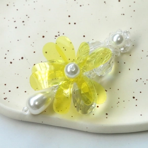 Detailed macro view of a handmade yellow acrylic flower hair clip with pearls and crystal beads