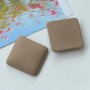 Close-up of matte khaki square resin charms with rounded edges for DIY jewelry making