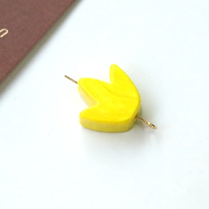 Dettaglio di pendente a foglia gialla con perno in metallo dorato per creazione gioielli