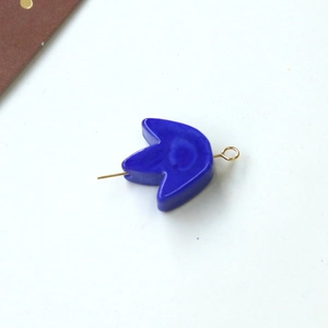 Primo piano di un ciondolo a petalo blu smaltato con perno in metallo dorato per gioielli DIY