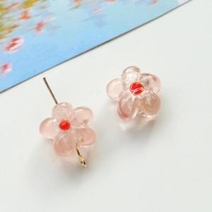 Detailed macro shot of pink glass flower beads for DIY jewelry with gold metal pins