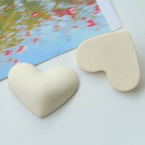 Close-up of heart-shaped matte resin charms in cream white for DIY jewelry making