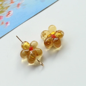 Macro detail of amber glass flower bead with gold leaf inlay and red center on a gold pin