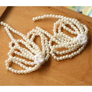 Detail of elegant white faux pearls with bright luster arranged on a wooden tray