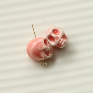 Macro shot of 3D pink resin skull charms with glossy finish and golden metal hooks