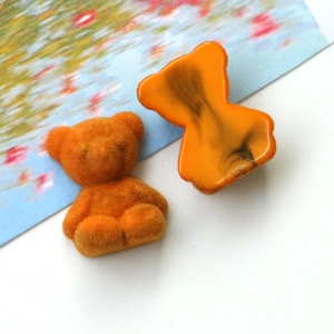 Detail of orange flocked and translucent acrylic bear charms for jewelry and DIY crafts