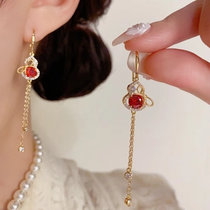 Detail of elegant gold gourd earrings with red gemstones and sparkling long tassels