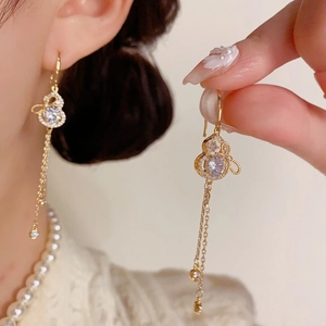 Elegant gold gourd tassel earrings with sparkling crystals shown on model