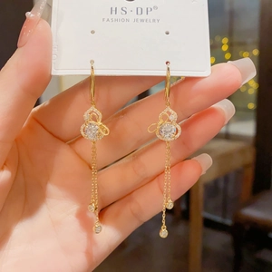 Detailed macro view of golden gourd earrings with sparkling zircon tassels and hooks