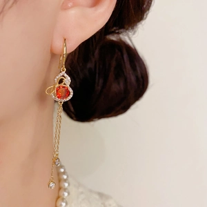 Detail of gold gourd tassel earrings with sparkling rhinestones and a red gemstone