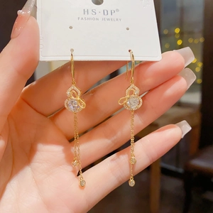 Close-up of gold gourd earrings with long tassels and sparkling zircon stones on a card