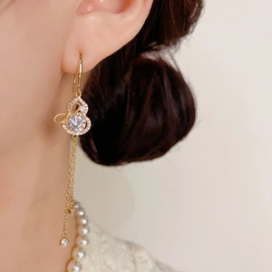 Macro shot of hulu tassel earrings with sparkling diamonds on gold plated metal