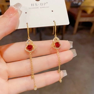 Detail of long tassel earrings with red gourd pendant and gold-plated chain fringe