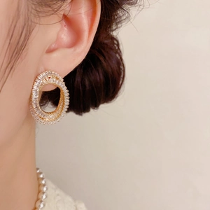 Gros plan de boucles d'oreilles ovales dorées avec cristaux de zircon sur un modèle