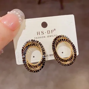 Gros plan de boucles d'oreilles ovales dorées avec pierres noires et aiguilles en argent S925