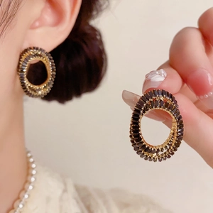 Vue détaillée des boucles d'oreilles ovales soleil avec pierres noires et base dorée